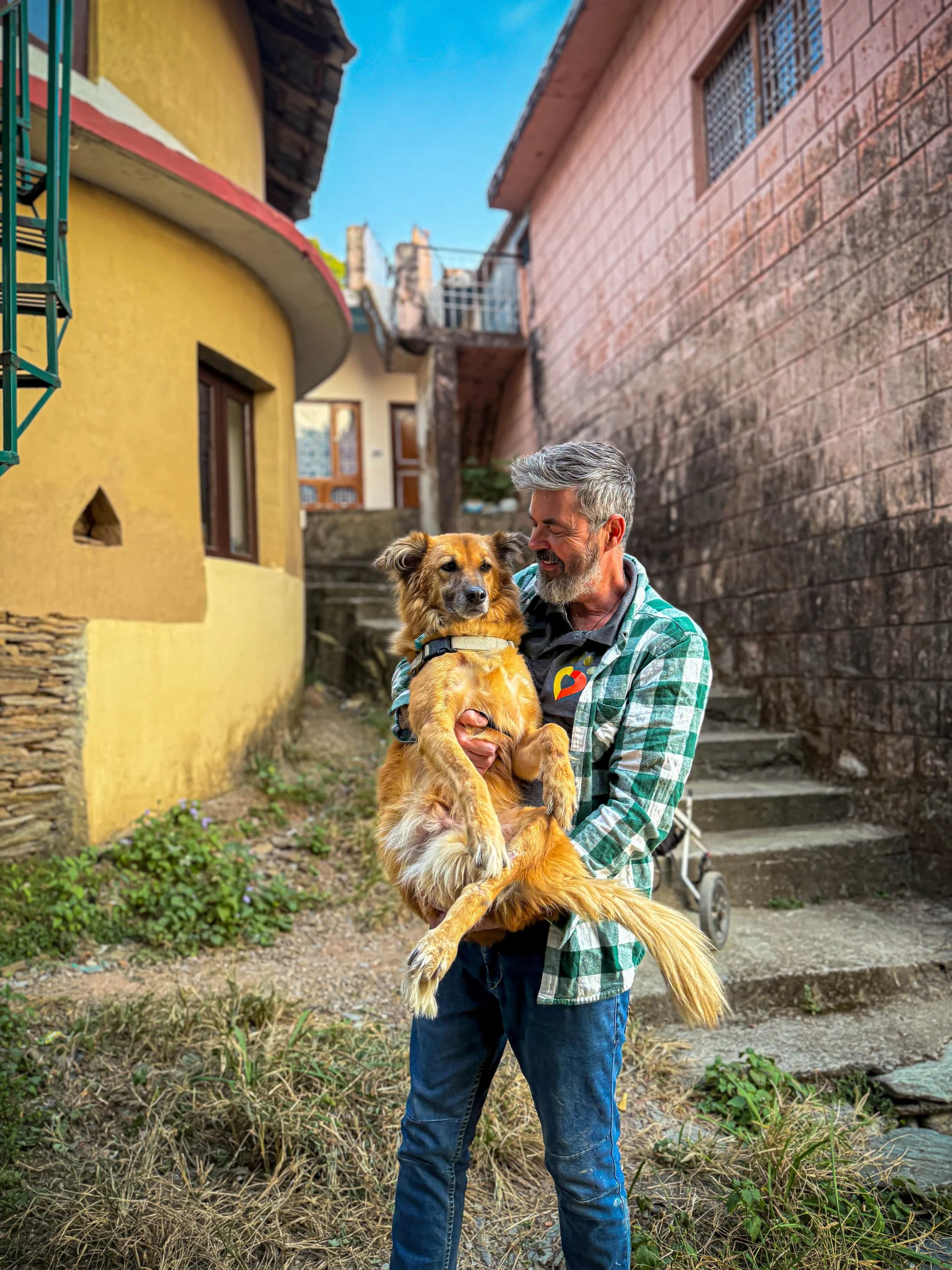 Animal welfare worker from Dharamshala Animal Rescue in India holding a rescued dog during a local community initiative.