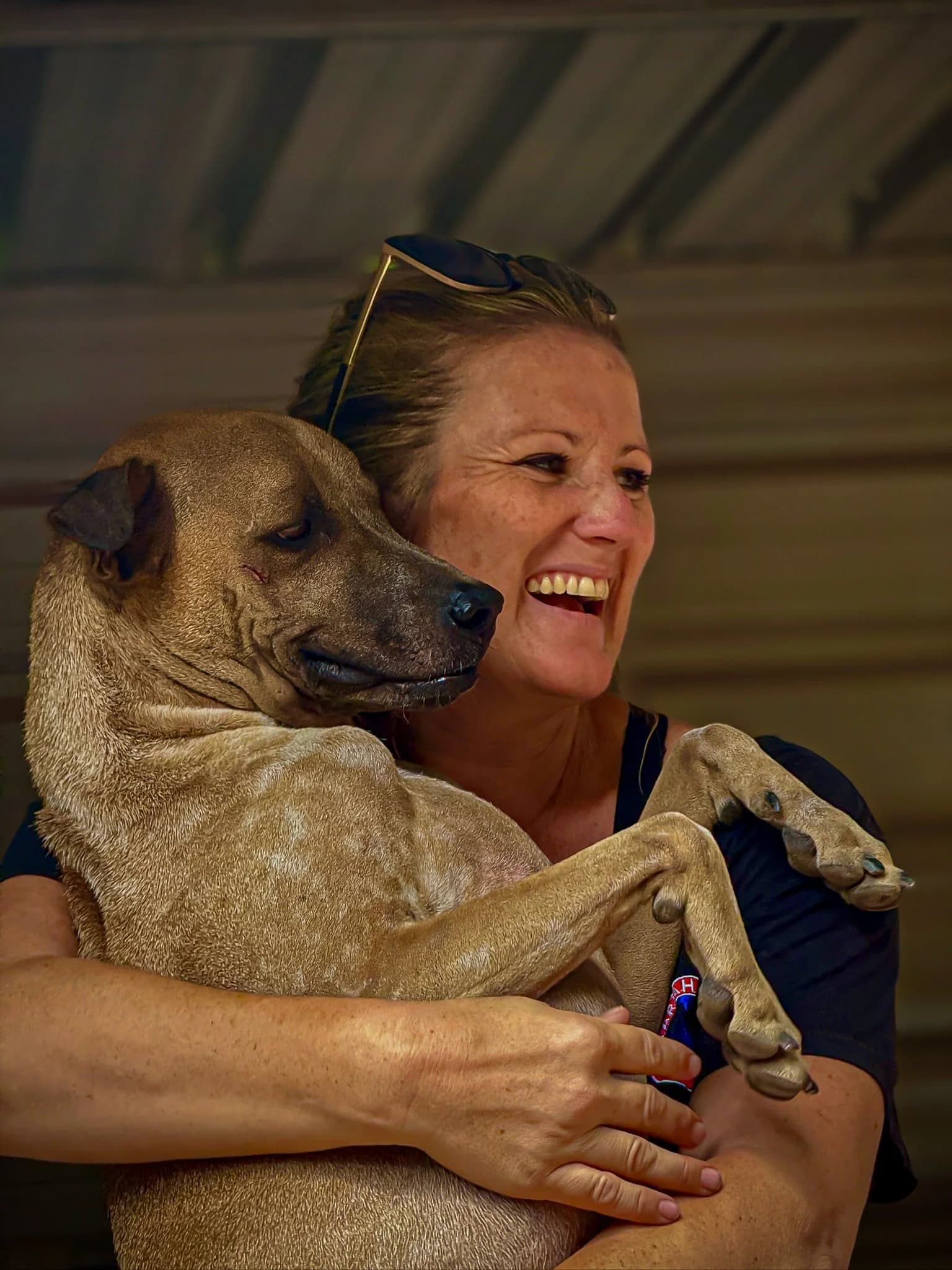 Team member from Pariah Dogs Samui holding a rescued dog during an animal welfare initiative in Thailand.