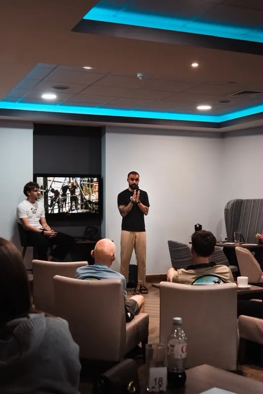 Someone speaking to a seated group in a lounge