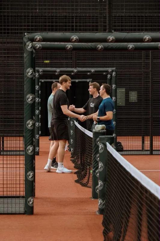 People talking across the net on a padel court