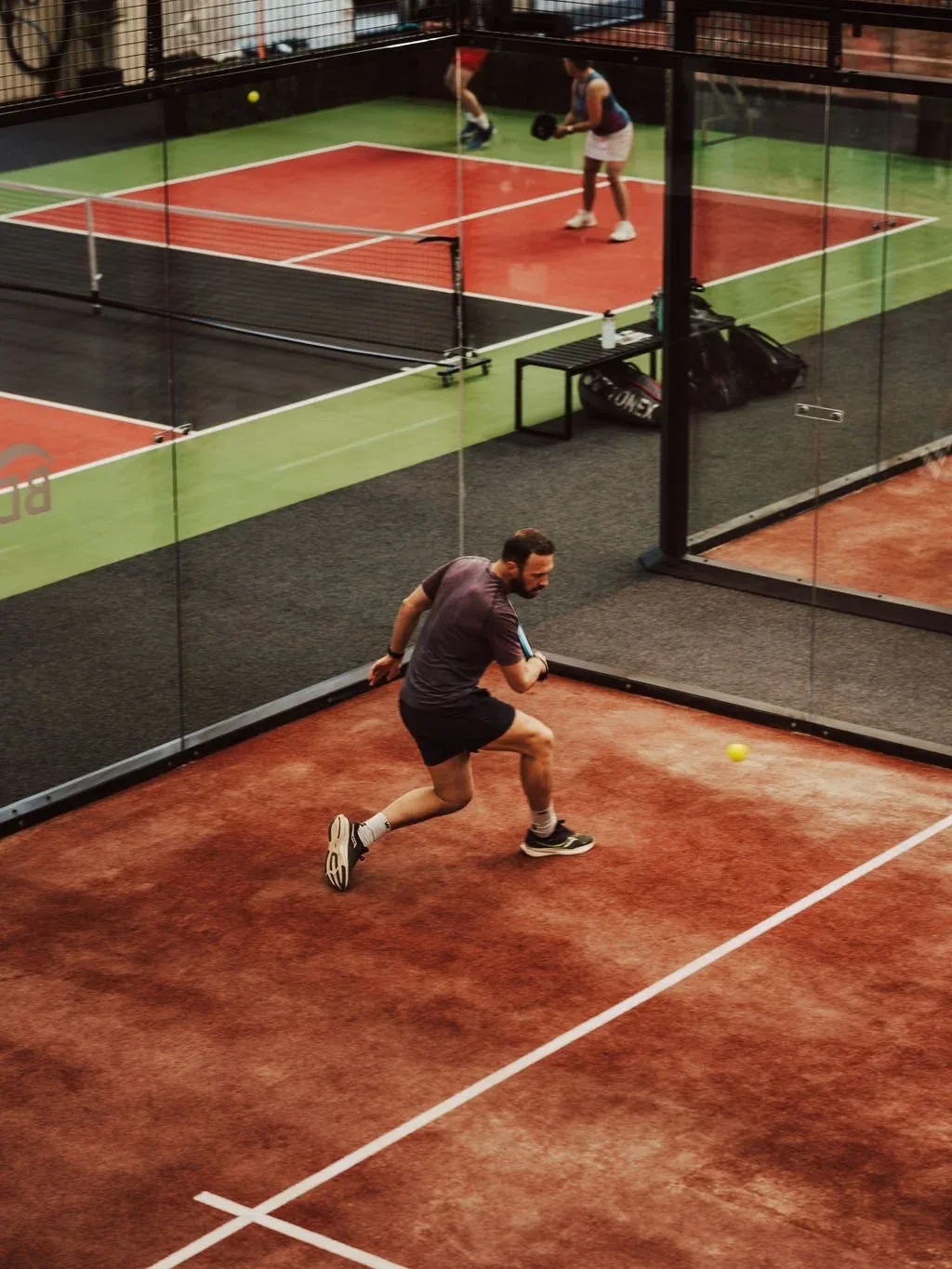 A player reaching for the ball on the courts at Padel & Play