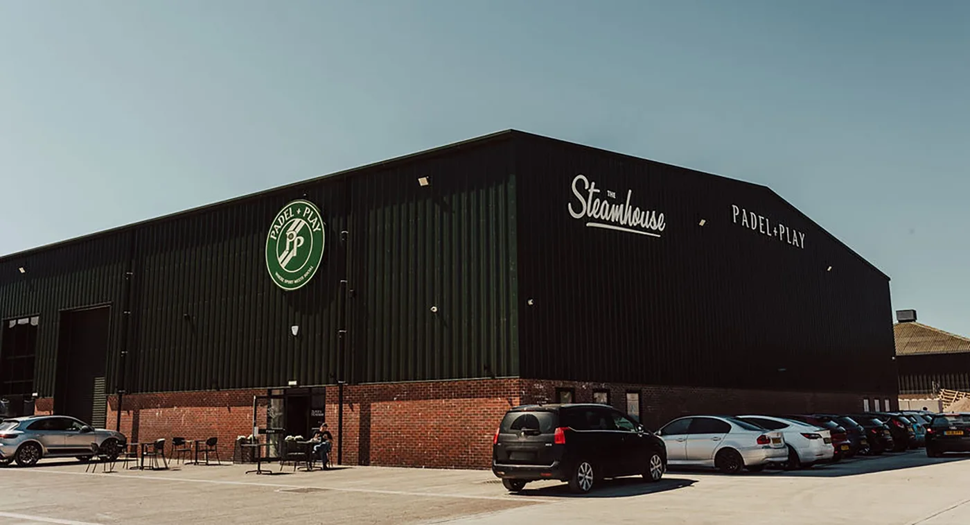 The outside of Padel & Play, Stratford-upon-Avon, with the sign above the entrance and the car park in front